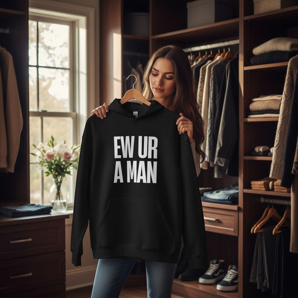 Eine Frau hält einen schwarzen spiritualsavagee Unisex-Hoodie mit dem weißen Aufdruck EW UR A MAN in einem Ankleidezimmer.