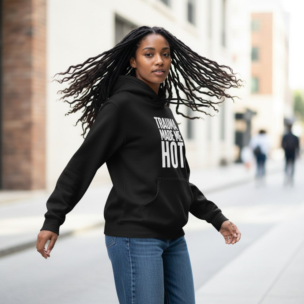 Eine Frau mit Dreadlocks trägt den schwarzen spiritualsavagee Unisex-Hoodie mit dem Aufdruck TRAUMA MADE ME HOT.