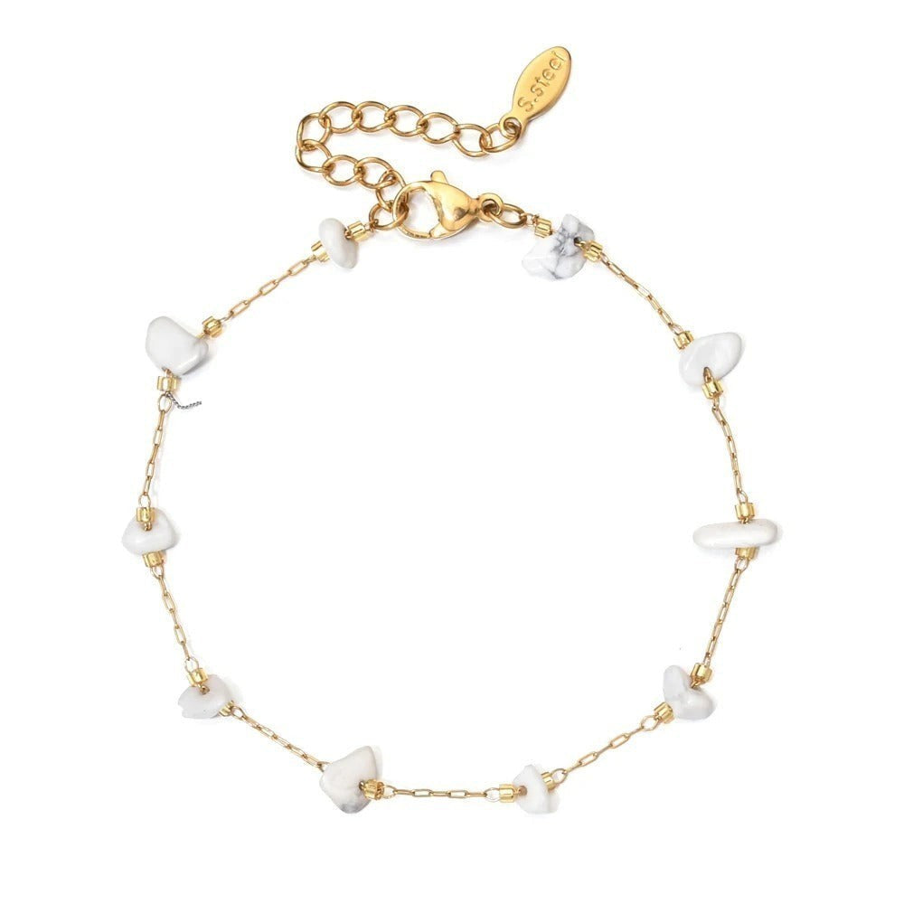 Entdecke das Stillness Bracelet: ein filigranes, goldfarbenes Armband mit weißen Natursteinen – ein stilvolles Symbol für Ruhe und innere Stärke.
