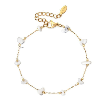 Entdecke das Stillness Bracelet: ein filigranes, goldfarbenes Armband mit weißen Natursteinen – ein stilvolles Symbol für Ruhe und innere Stärke.
