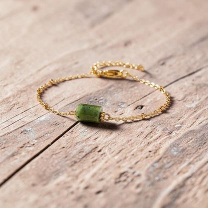 spiritualsavagee Jade Balance Armband mit grünem Naturstein und vergoldeter Kette auf einem hellen Steinpodest