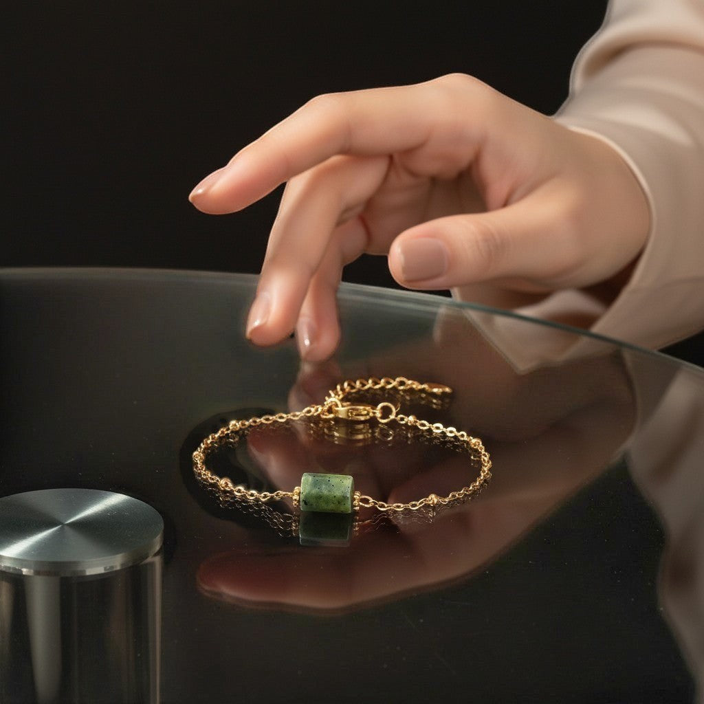 spiritualsavagee Jade Balance Armband mit grünem Naturstein und vergoldeter Kette auf einem glatten, schwarzen Tisch