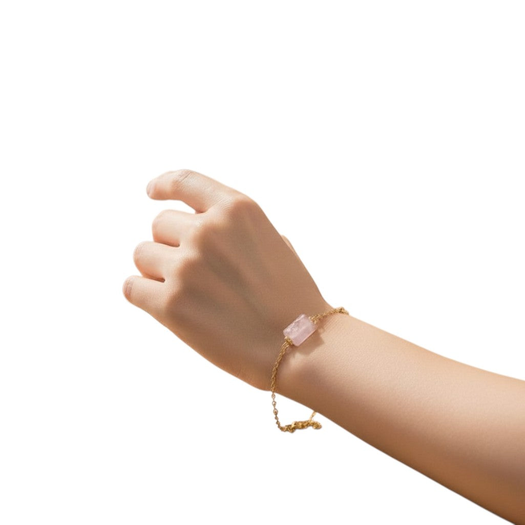 spiritualsavagee Armband aus natürlichem Rosenquarz mit vergoldeten Akzenten an einem Handgelenk bei einer Tasse Tee