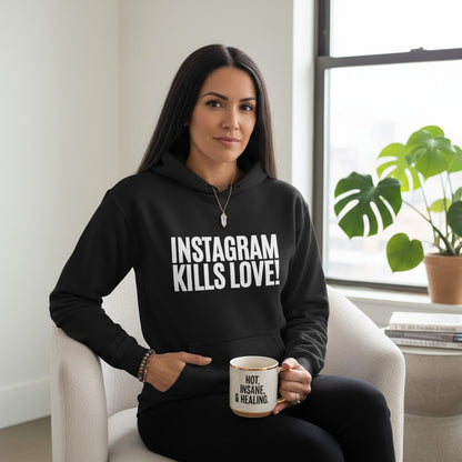 spiritualsavagee schwarzer Unisex-Hoodie mit weißem Instagram Kills Love Aufdruck, getragen von einer Frau im Sessel