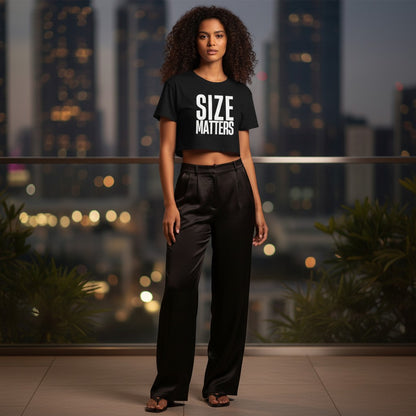 spiritualsavagee schwarzes bauchfreies T-Shirt mit weißem Aufdruck SIZE MATTERS an einer Frau vor nächtlicher Skyline