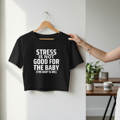 Schwarzes spiritualsavagee Crop-Top mit weißem Aufdruck Stress Is Not Good For The Baby an einem Holzkleiderbügel.