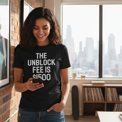 Ein Mann trägt ein schwarzes spiritualsavagee T-Shirt mit dem weißen Aufdruck THE UNBLOCK FEE IS $1500 in einem Loft.