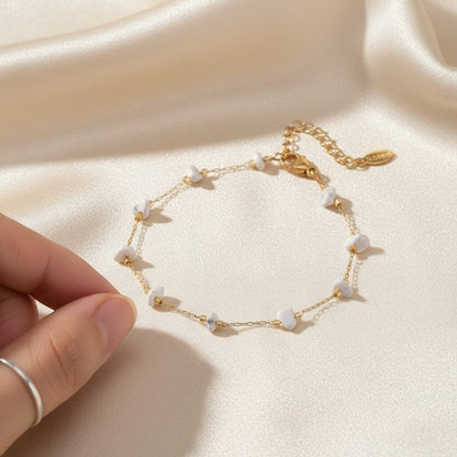 spiritualsavagee The Stillness Bracelet aus goldfarbenem Edelstahl mit zarten weißen Natursteinen auf Seidenstoff